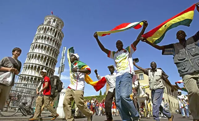 FILE - Senegalese soccer supporters wave their national flags as they celebrate in front of Pisa's historical leaning tower, Italy, May 31, 2002, shortly after Senegal defeated France in the World Cup. (AP Photo/Fabio Muzzi, File)