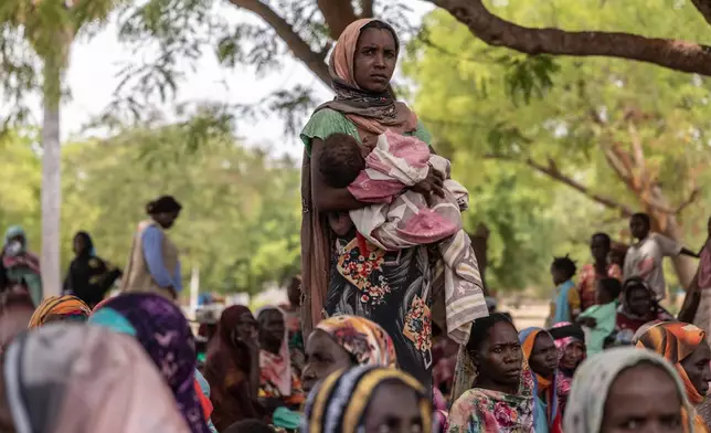 A woman holds her baby outside the registration center for new refugees on the outskirts of the Korsi Refugee Camp in Birao, Central African Republic, Thursday, March 26, 2026. (AP Photo/Caitlin Kelly)