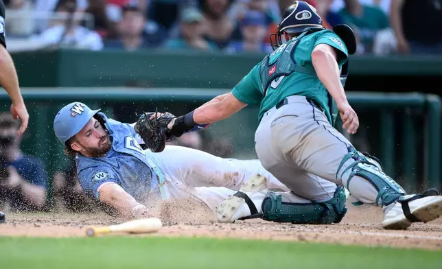Washington Nationals' Dylan Crews, left, is safe at home plate against Seattle Mariners catcher Mitch Garver, right, during the seventh inning of a baseball game, Saturday, June 13, 2026, in Washington. (AP Photo/Nick Wass)
