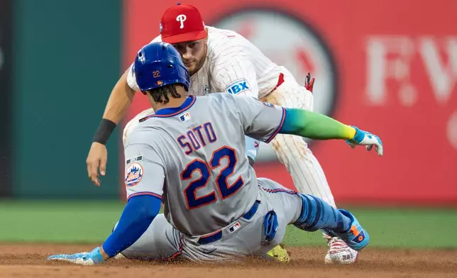 Philadelphia Phillies shortstop Trea Turner, right, tags out New York Mets' Juan Soto, left, who was trying to stretch his hit into a double during the third inning of a baseball game, Sunday, June 21, 2026, in Philadelphia. (AP Photo/Chris Szagola)