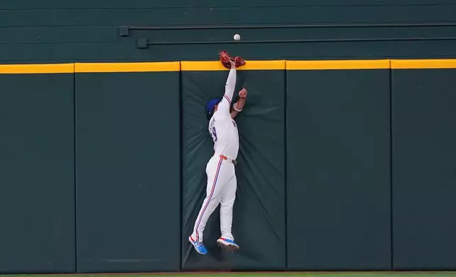 Texas Rangers center fielder Alejandro Osuna can't reach the home run ball at the wall hit by Minnesota Twins' Trevor Larnach during the fourth inning of a baseball game, Thursday, June 18, 2026, in Arlington, Texas. (AP Photo/LM Otero)