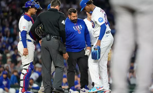 Chicago Cubs starting pitcher Edward Cabrera, right, is checked by a team trainer after an injury during the fifth inning of a baseball game against the Colorado Rockies in Chicago, Tuesday, June 16, 2026. (AP Photo/Nam Y. Huh)