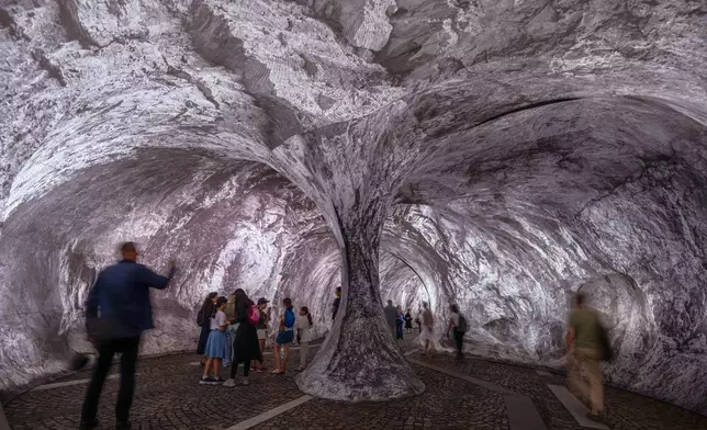 Visitors walk into the artwork "The Pont Neuf Cave" by French street artist JR on the Pont Neuf bridge, Tuesday, June 16, 2026, in Paris, open to the public from June 15 to 28. (AP Photo/Aurelien Morissard)