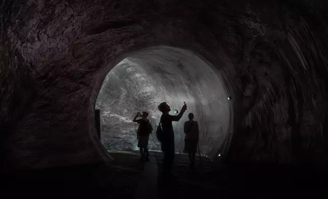 Visitors walk into the artwork "The Pont Neuf Cave" by French street artist JR on the Pont Neuf bridge, Tuesday, June 16, 2026, in Paris, open to the public from June 15 to 28. (AP Photo/Aurelien Morissard)