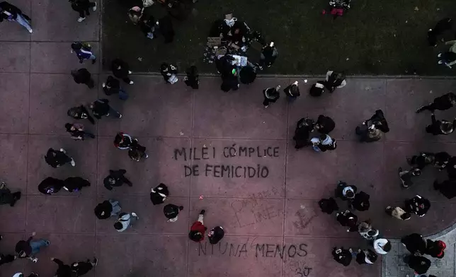 Demontrators walk near a painting reading in Spanish " Milei femicide accomplice" referring to President Javier Milei during a march marking the anniversary of the "Ni Una Menos" (Not One Fewer) women's movement in Buenos Aires, Argentina, Wednesday, June 3, 2026. (AP Photo/Natacha Pisarenko)