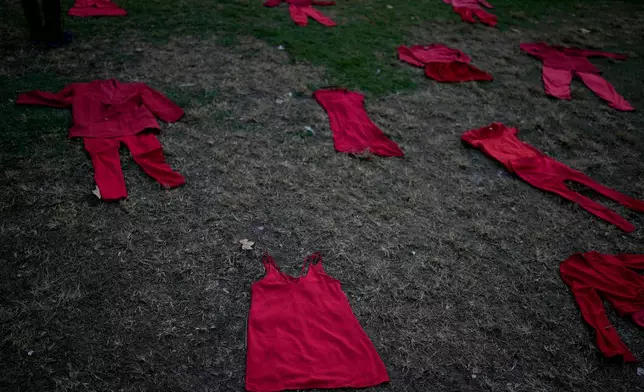 FILE - Outfits representing women who were disappeared or murdered lie on the grass outside Congress during a march marking the ninth anniversary of the "Ni Una Menos" (Not One Fewer) women's movement in Buenos Aires, Argentina, June 3, 2024. (AP Photo/Natacha Pisarenko, File)