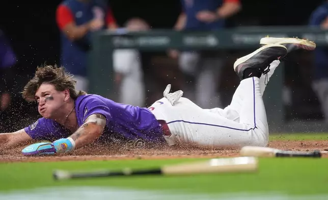 Colorado Rockies' Cole Carrigg dives into home plate to score the winning run on a three-run walkoff triple hit by Jake McCarthy off Boston Red Sox relief pitcher Aroldis Chapman in the ninth inning of a baseball game Monday, June 22, 2026, in Denver. (AP Photo/David Zalubowski)