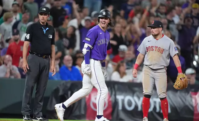 Colorado Rockies' Jake McCarthy, center, celebrates after his three-run walkoff triple as third base umpire John Tumpane, left, and Boston Red Sox third baseman Caleb Durbin, right, look on in the ninth inning of a baseball game Monday, June 22, 2026, in Denver. (AP Photo/David Zalubowski)