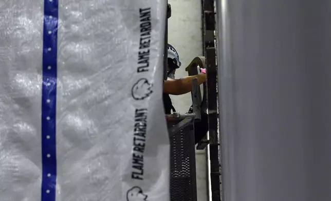 A worker removes a letter from President Donald Trump's name from the wall of the John F. Kennedy Center for the Performing Arts in Washington, Saturday, June 13, 2026. (AP Photo/Cliff Owen)