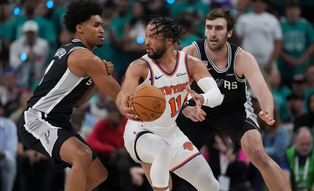 New York Knicks guard Jalen Brunson (11) spins as San Antonio Spurs guard Dylan Harper, left, defends during the first half of Game 1 of the NBA Finals basketball series, Wednesday, June 3, 2026, in San Antonio. (AP Photo/Eric Gay)