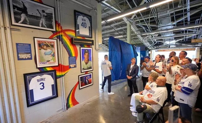 Attendees reacts during a ceremony prior to a baseball game to unveil a tribute to LGBTQ+ trailblazers and former Los Angeles Dodgers players Billy Bean and Glenn Burke, who were among the first professional athletes to identify as gay, Friday, June 5, 2026, in Los Angeles. (AP Photo/Mark J. Terrill)