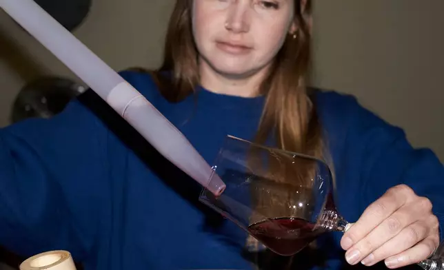 Natasha Jacka pours wine from an oak barrel into a glass using a "wine thief" in Cape Town, South Africa, Thursday, June 4, 2026. (AP Photo/Neil Shaw)