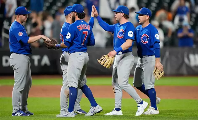 Chicago Cubs' Dansby Swanson (7) hands the game ball to pitcher Jacob Webb as they celebrate with teammates after the second baseball game of a doubleheader against the New York Mets Wednesday, June 24, 2026, in New York. (AP Photo/Frank Franklin II)