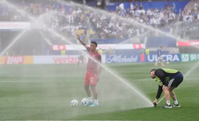 Switzerland's Dan Ndoye (11) tries to warm up as sprinklers are watering the field ahead the World Cup Group B soccer match between Switzerland and Bosnia in Inglewood, Calif, near Los Angeles, Thursday, June 18, 2026. (AP Photo/Gregory Bull)