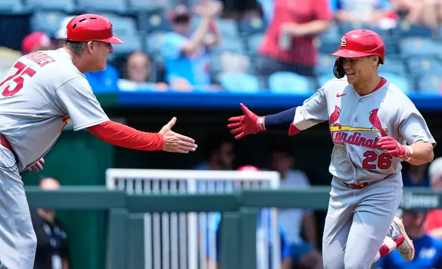 St. Louis Cardinals' JJ Wetherholt (26) celebrates with third base coach Ron 'pop' Warner (75) after hitting a solo home run during the first inning of a baseball game against the Kansas City Royals, Sunday, June 21, 2026, in Kansas City, Mo. (AP Photo/Charlie Riedel)