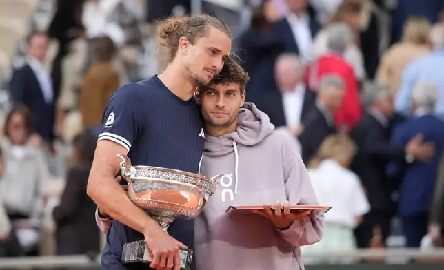 Winner Alexander Zverev of Germany, left, and second placed Flavio Cobolli of Italy hug with their trophies after the men's final match at the French Open tennis tournament in Paris, Sunday, June 7, 2026. (AP Photo/Christophe Ena)