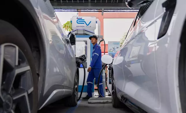 Khatawut Junsongsaeng, a charging station manager, walks past two Chinese-made electric vehicles at a parking lot in Bangkok, Thailand on June 4, 2026. (AP Photo/Anton L. Delgado)