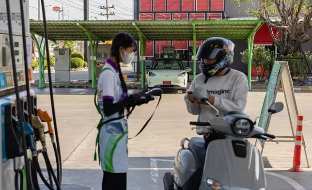 A motorcyclist fills his tank in front of an electric vehicle charging terminal at a gas station in Thailand's Nakorn Pathom province on May 28, 2026. (AP Photo/Anton L. Delgado)
