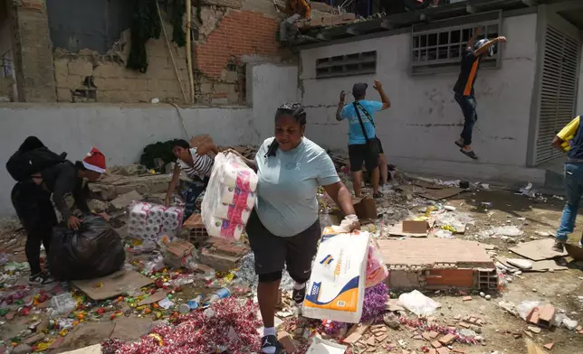 People take goods from damaged stores a day after earthquakes and aftershocks struck Catia La Mar, Venezuela, Thursday, June 25, 2026. (AP Photo/Jonathan Lanza)
