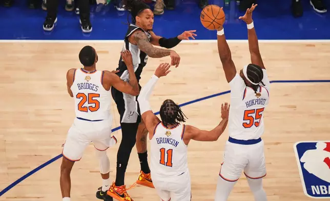 San Antonio Spurs guard Devin Vassell passes the ball as New York Knicks guard Mikal Bridges (25), guard Jalen Brunson (11) and center Ariel Hukporti (55) defend during the first half of Game 4 of the NBA Finals basketball series, Wednesday, June 10, 2026, in New York. (AP Photo/Frank Franklin II)