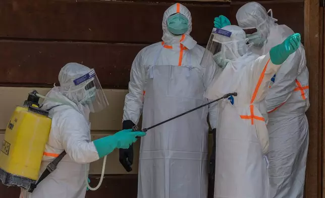 Health workers disinfect themselves after preparing the body of an Ebola victim at Citadelle Clinic in Bunia, Congo, Friday, June 12, 2026. (AP Photo/Moses Sawasawa)