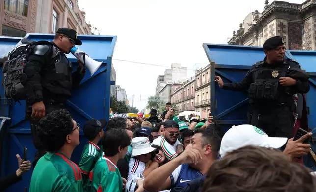 Law enforcement guard a barricade as fans funnel their way through to a fan festival area to watch the World Cup Group A soccer match between Mexico and South Africa in Mexico City, Thursday, June 11, 2026. (AP Photo/Ashtin Barker)