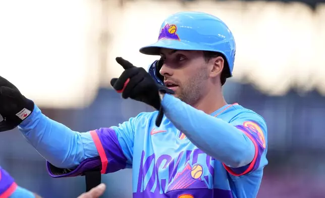 Colorado Rockies' Edouard Julien gestures to the dugout after reaching first base on an RBI single off Milwaukee Brewers starting pitcher Brandon Sproat in the second inning of a baseball game Friday, June 5, 2026, in Denver. (AP Photo/David Zalubowski)
