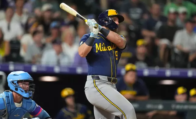 Milwaukee Brewers' Jake Bauers, right, follows the flight of his double that drove in two runs off Colorado Rockies relief pitcher Juan Mejia in the 10th inning of a baseball game Friday, June 5, 2026, in Denver. (AP Photo/David Zalubowski)