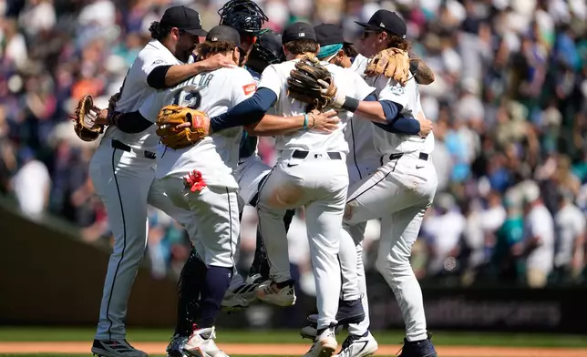 The Seattle Mariners infield, including relief pitcher Andrés Muñoz, far left, first baseman Josh Naylor (12), second baseman Cole Young and shortstop Colt Emerson, right, celebrate a win over the Baltimore Orioles after a baseball game, Thursday, June 18, 2026, in Seattle. (AP Photo/Lindsey Wasson)