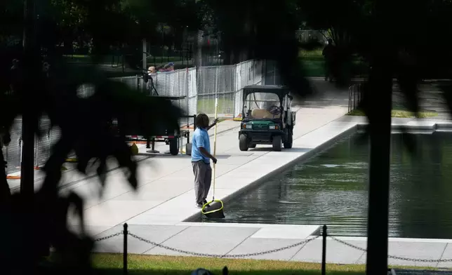 A worker uses a a pool skimmer net at the Lincoln Memorial Reflecting Pool Friday, June 26, 2026, in Washington. (AP Photo/Carolyn Kaster)