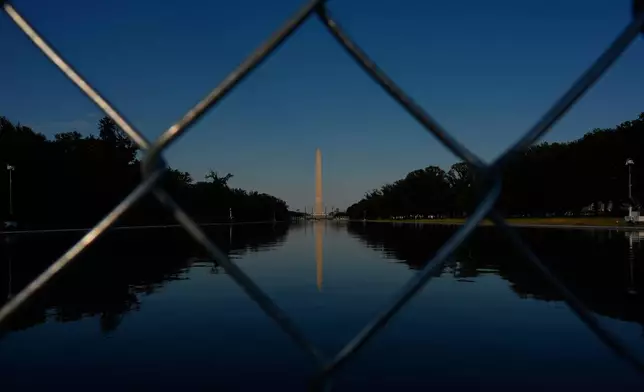 The Washington Monument, reflected in the Lincoln Memorial Reflecting Pool, is seen behind a chain link fence Thursday, June 25, 2026, in Washington. (AP Photo/Carolyn Kaster)