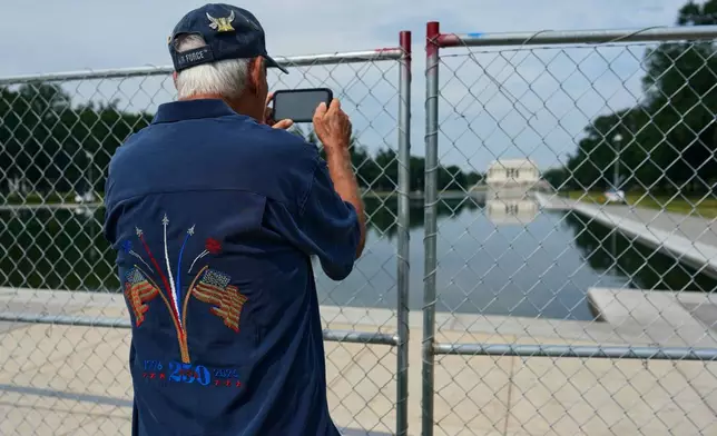 Air Force veteran David Stanton takes a photo of the Lincoln Memorial Reflecting Pool and the Lincoln Memorial from behind a chain link fence Friday, June 26, 2026, in Washington. (AP Photo/Carolyn Kaster)