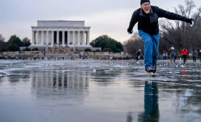 FILE - The Lincoln Memorial is visible as Dan DeMocker, of Tacoma Park, Md., slides pieces of ice toward his family as he ice skates on the frozen Reflecting Pool on the National Mall in Washington, Dec. 26, 2022. (AP Photo/Andrew Harnik, File)