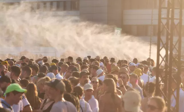 Thousands of fans are celebrating at a concert by techno star Paul Kalkbrenner on the Heiligengeistfeld while a water cannon is in operation on Saturday, June 27, 2026 in Hamburg, Germany. (Marcus Golejewski/dpa via AP)