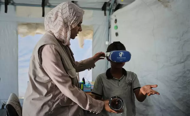 Ahmed Matar, 11, participates in a psychological support session using a virtual reality headset in a tent operated by a medical technology team in Zawaida, central Gaza Strip, Wednesday, June 17, 2026. (AP Photo/Abdel Kareem Hana)