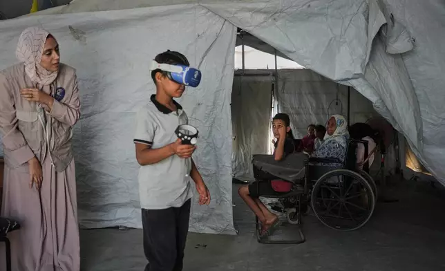 Ahmed Matar, 11, participates in a psychological support session using a virtual reality headset in a tent operated by a medical technology team in Zawaida, central Gaza Strip, Wednesday, June 17, 2026. (AP Photo/Abdel Kareem Hana)