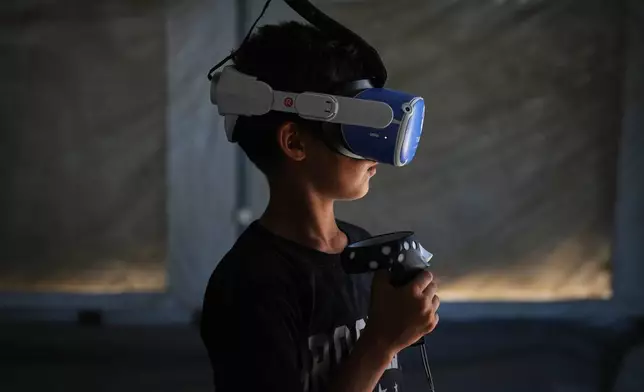 Mohammed Matar, 11, participates in a psychological support session using a virtual reality headset in a tent operated by a medical technology team in Zawaida, central Gaza Strip, Wednesday, June 17, 2026. (AP Photo/Abdel Kareem Hana)