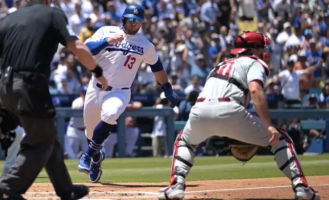 Los Angeles Dodgers' Max Muncy (13) beats a throw to Philadelphia Phillies catcher J.T. Realmuto, right, for a run during the second inning of a baseball game Sunday, May 31, 2026, in Los Angeles. (AP Photo/Jayne Kamin-Oncea)