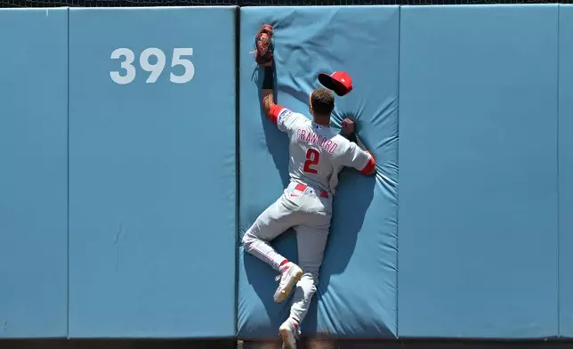Philadelphia Phillies center fielder Justin Crawford crashes into the wall after making a leaping catch of a ball hit by Los Angeles Dodgers' Andy Pages during the first inning of a baseball game Sunday, May 31, 2026, in Los Angeles. (AP Photo/Jayne Kamin-Oncea)