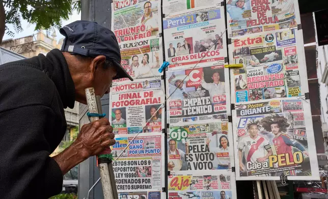 A man reads newspapers' front pages on the previous day's presidential election runoff in Lima, Peru, Monday, June 8, 2026. (AP Photo/Rodrigo Abd)