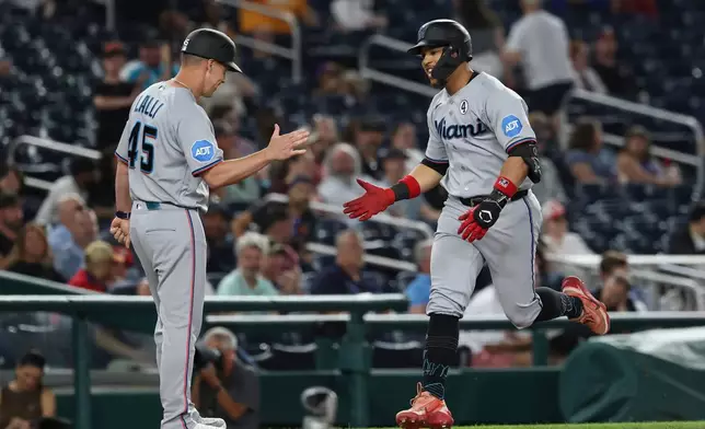 Miami Marlins' Heriberto Hernández, right, is greeted by third base coach Blake Lalli (45) as he runs the bases after hitting two-run home run off Washington Nationals pitcher Mitchell Parker which also scored Jakob Marsee during the ninth inning of a baseball game, Tuesday, June 2, 2026, in Washington. (AP Photo/Terrance Williams)