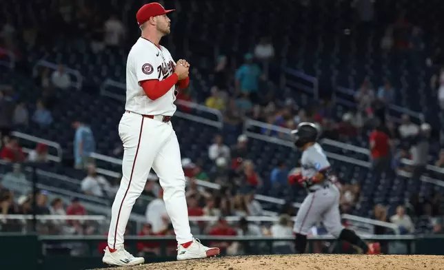 Washington Nationals pitcher Mitchell Parker rubs a new baseball after surrendering a two-run home run to Miami Marlins' Heriberto Hernández as he runs the bases during the ninth inning of a baseball game, Tuesday, June 2, 2026, in Washington. (AP Photo/Terrance Williams)