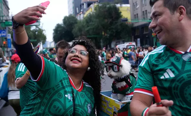 A fan, left, takes a photo with a dog named Osito, wearing a Mexico national soccer team jersey, next to Jorge Rangel before the World Cup Group A soccer match against South Korea in Mexico City, Thursday, June 18, 2026. (AP Photo/Marco Ugarte)