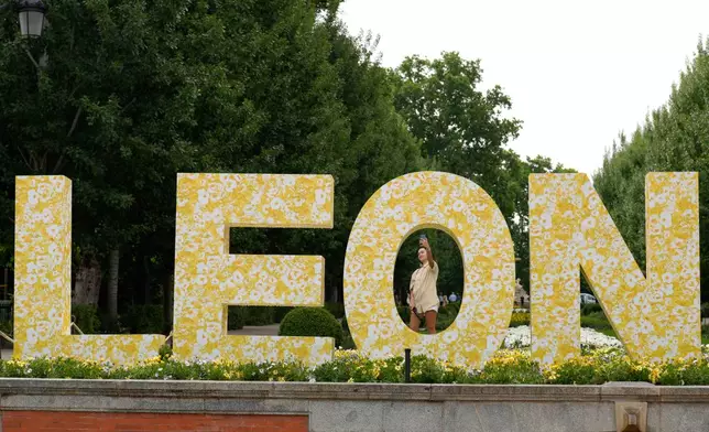 Visitors pose for photos next to a sign bearing the name of Pope Leo XIV in Madrid, Spain, Saturday, June 6, 2026. (AP Photo/Bernat Armangue)