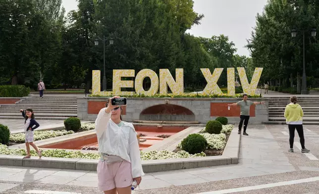 Visitors pose for photos beside a sign bearing the name of Pope Leo XIV in Madrid, Spain, Saturday, June 6, 2026. (AP Photo/Bernat Armangue)