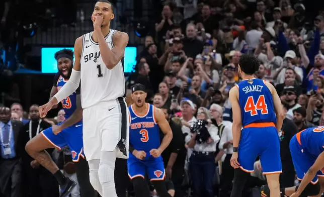San Antonio Spurs forward Victor Wembanyama walks off the court as time expires during the second half of Game 2 of the NBA Finals basketball series as New York Knicks guard Landry Shamet (44), guard Josh Hart (3), and center Mitchell Robinson (23) celebrate, Friday, June 5, 2026, in San Antonio. (AP Photo/Eric Gay)