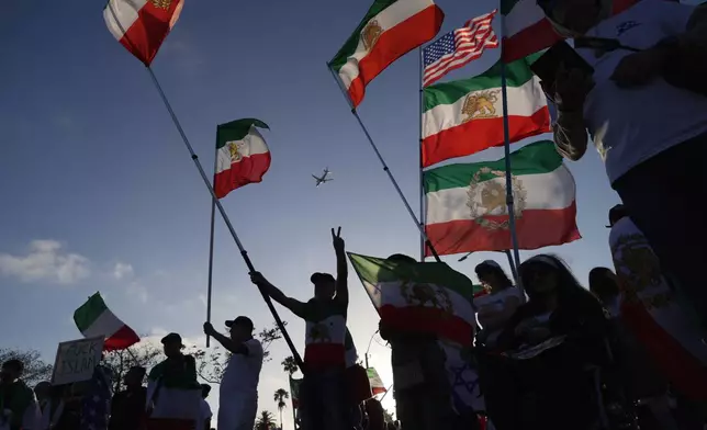 People wave pre-revolutionary Iranian flags during a protest outside Los Angeles Stadium before the World Cup Group G soccer match between Iran and New Zealand in Inglewood, Calif., near Los Angeles, Monday, June 15, 2026. (AP Photo/Ty ONeil)
