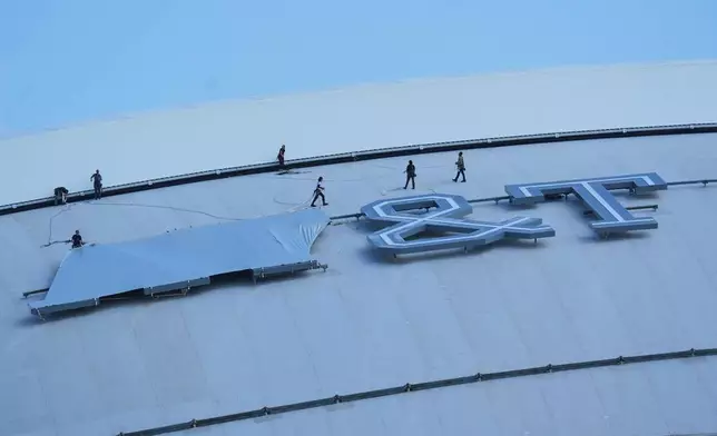 Workers cover signage on the exterior of AT&amp;T Stadium, which will be named Dallas Stadium during the 2026 FIFA World Cup soccer tournament, as preparations continue at the venue, Tuesday, June 2, 2026, in Arlington. (AP Photo/LM Otero)