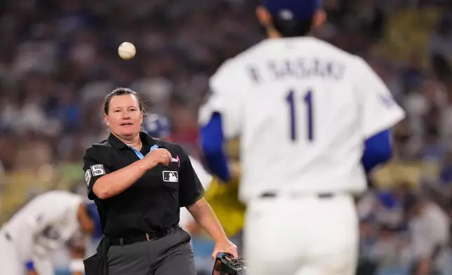Home plate umpire Jen Pawol tosses a ball to Los Angeles Dodgers starting pitcher Roki Sasaki as he comes out for the sixth inning of a baseball game against the Los Angeles Angels, Friday, June 5, 2026, in Los Angeles. (AP Photo/Mark J. Terrill)