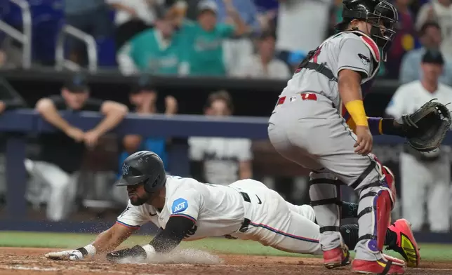 Miami Marlins' Otto Lopez scores on a double by Kyle Stowers as Arizona Diamondbacks catcher Gabriel Moreno (14) waits for the ball during the sixth inning of a baseball game Tuesday, June 9, 2026, in Miami. (AP Photo/Marta Lavandier)